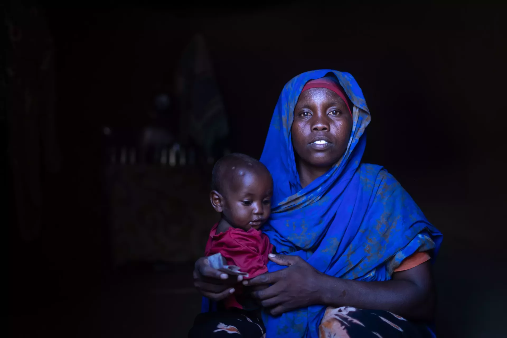 A women posing for the camera while holding her baby by her side
