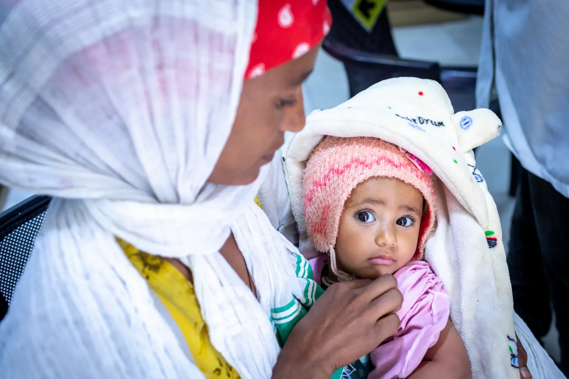 A mother holding her baby in her hand while the baby look straight into the camera