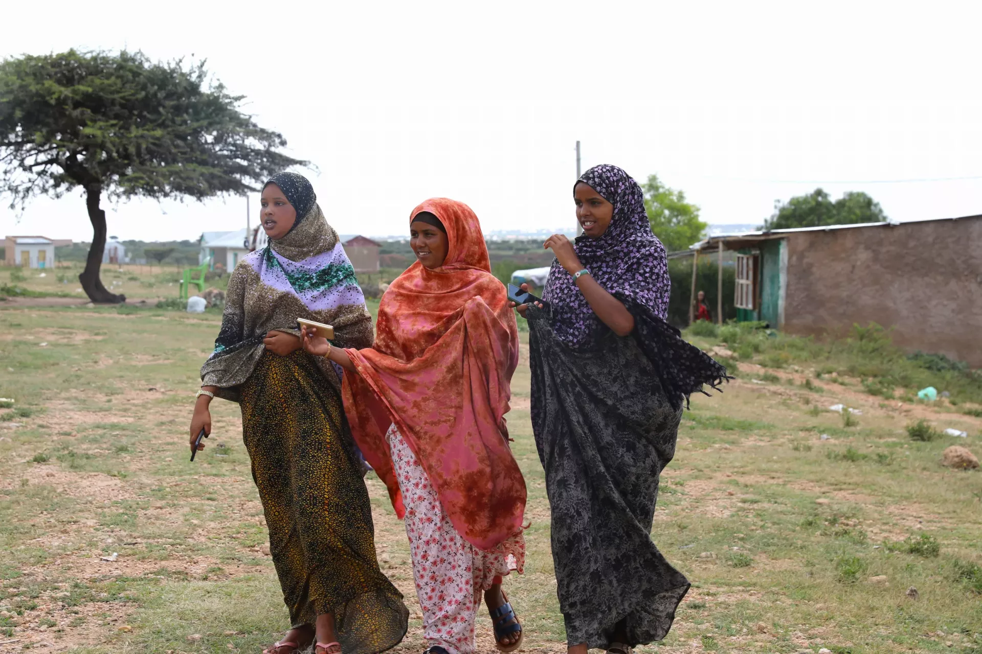 Three young community conversation facilitators walking to their destinations