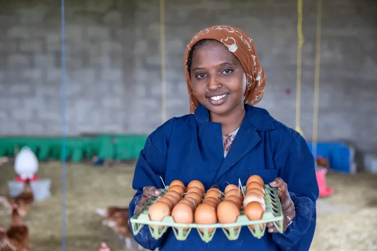 A girl smiles holding a tray full of eggs