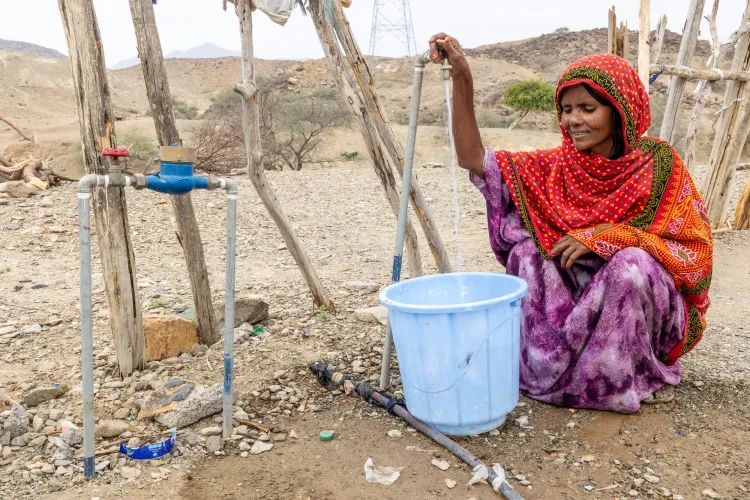 Woman fills a bucket from a tap. 