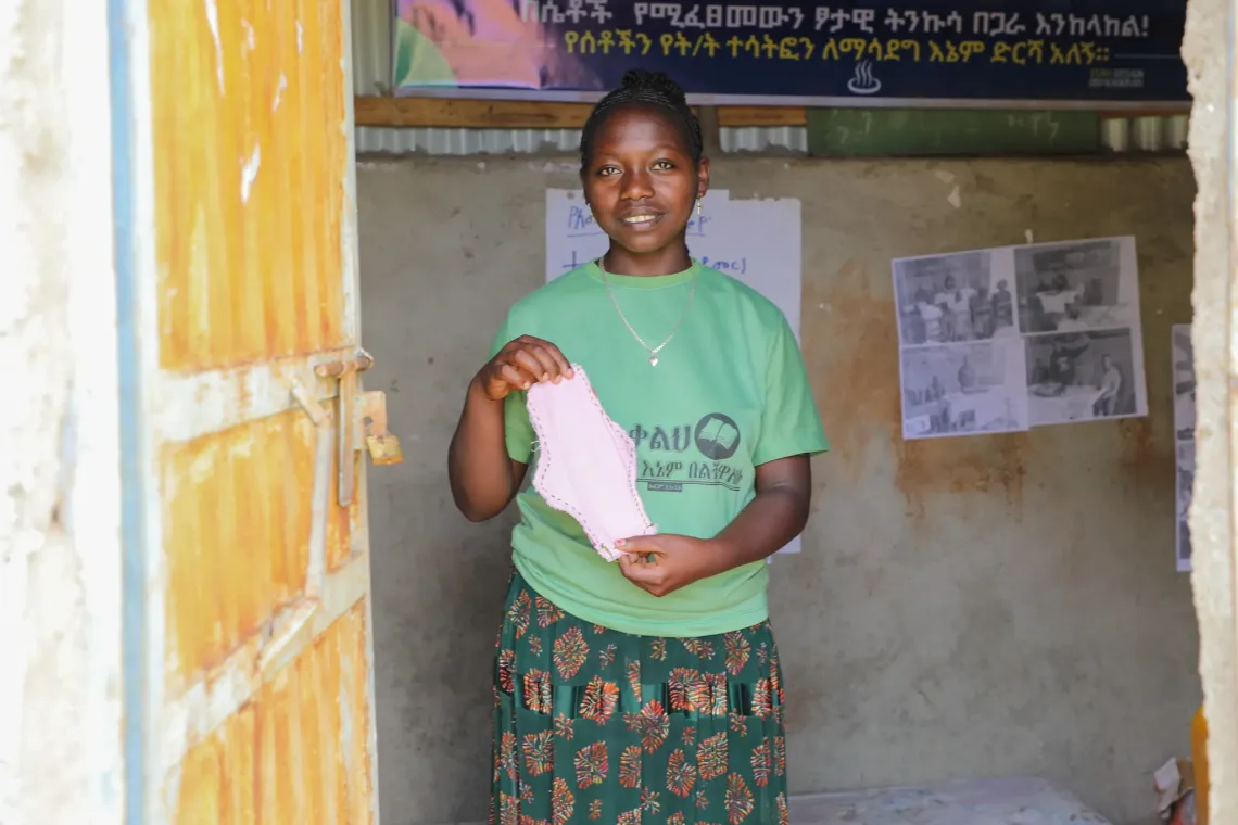 Bethelhem holding a reusable pad in her school's MHH room