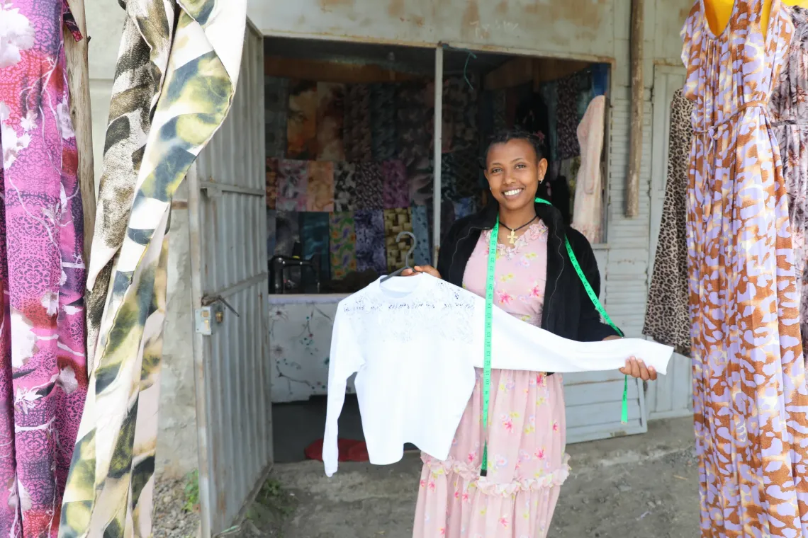 Tizibit Degefe standing outside of workshop/store  in Debre Berhan showcasing one of her creations.