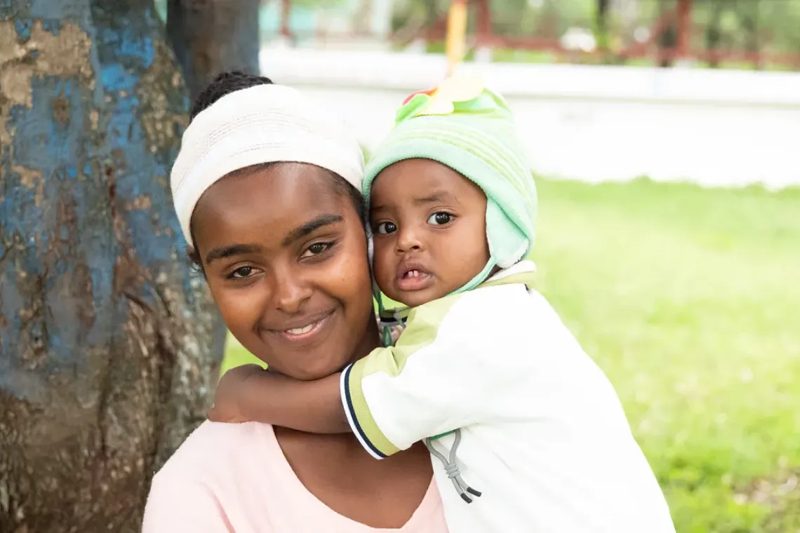 A mother and a baby posing for a camera with a smile