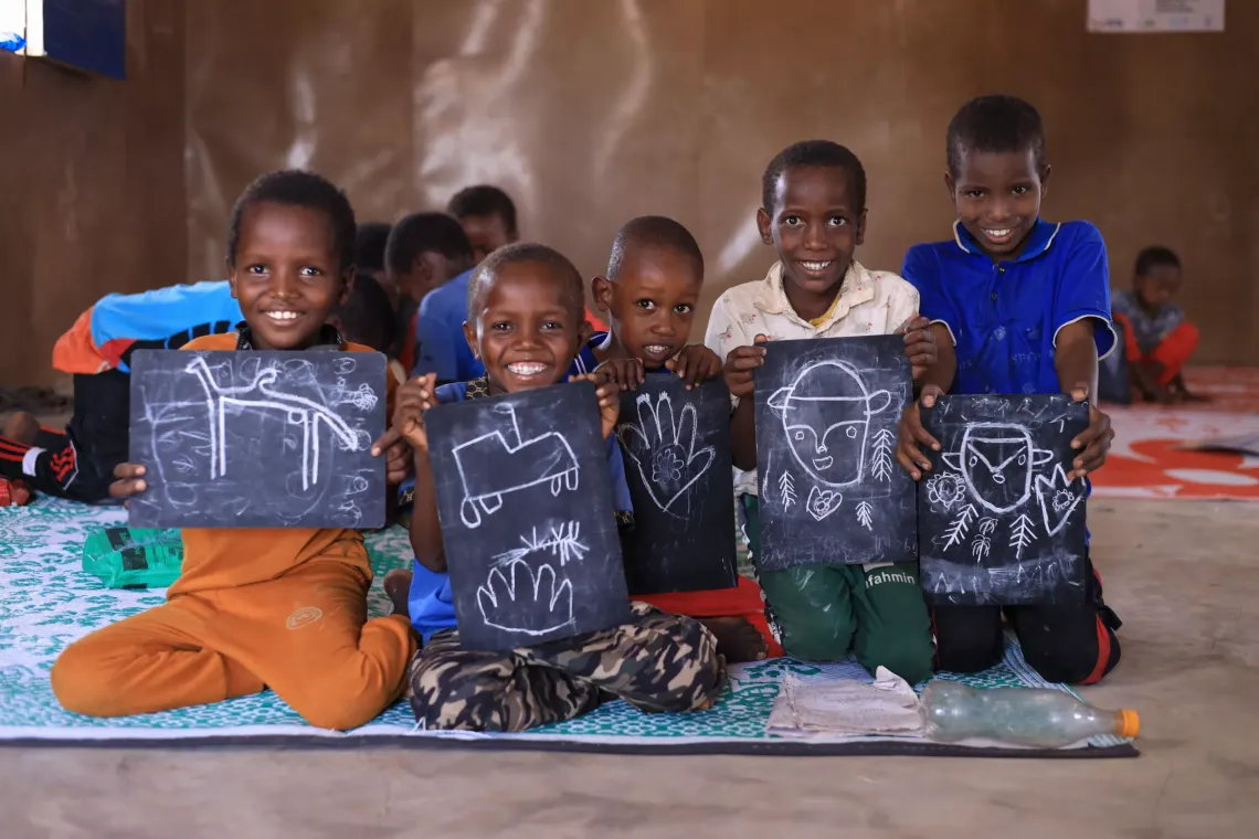 Children showing thier drawings the camera in their SPEED school classroom