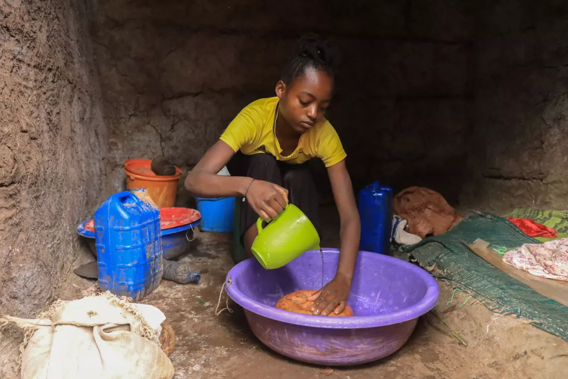A young girl washes dishes in the house.