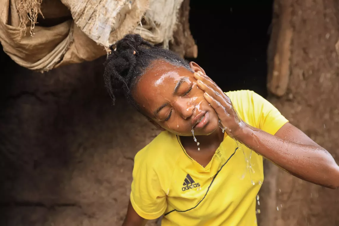 A young girl washing her face. 