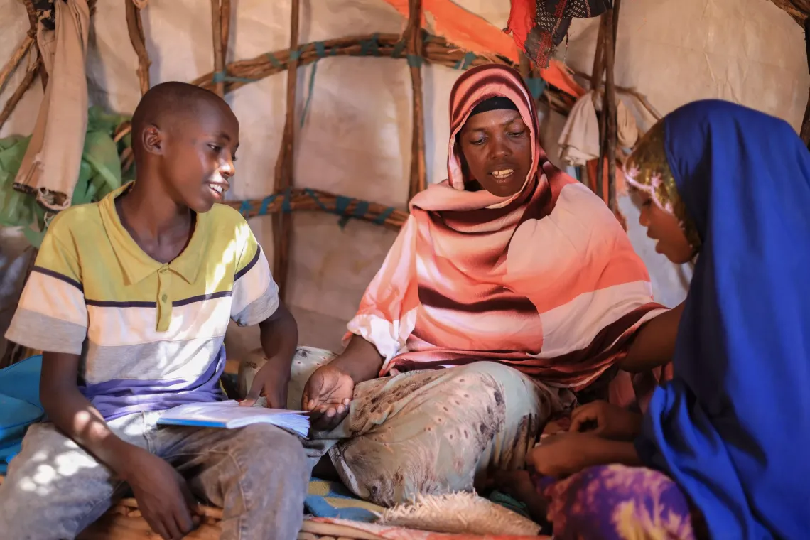 A mother sitting and talking with her two adolescents children in their home
