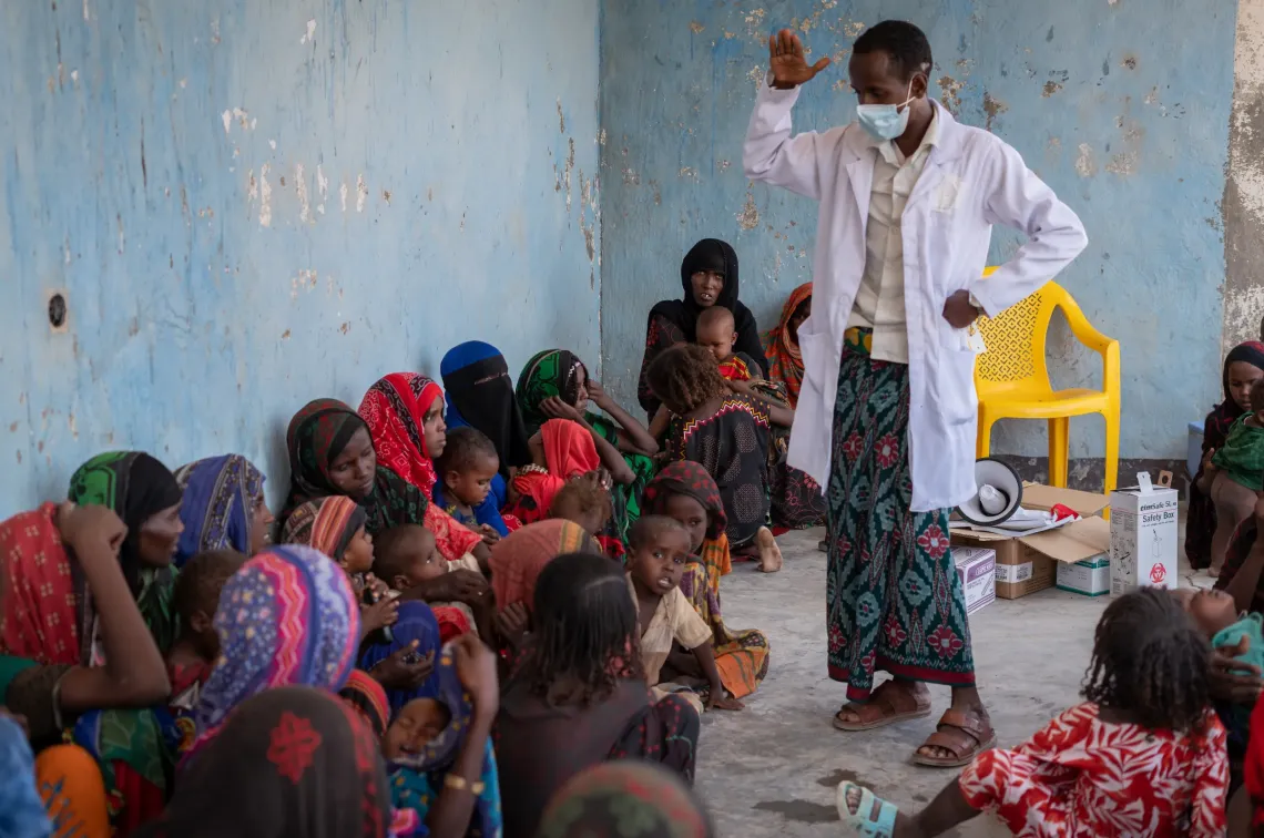 A health worker teaching mothers who are sitting in a around