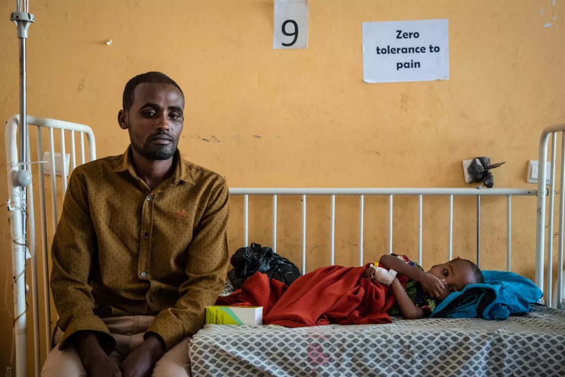 Ibrahim Abdi is sitting next to his 3-year-old daughter, Nesra Ibrahim. His wife has just had a baby and needed to stay at home. 