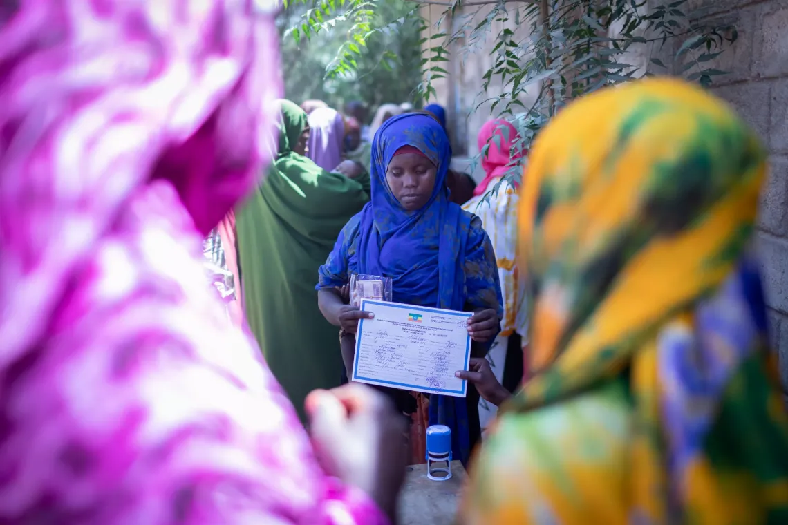 A women showing her baby's birth registration certificate to the camera