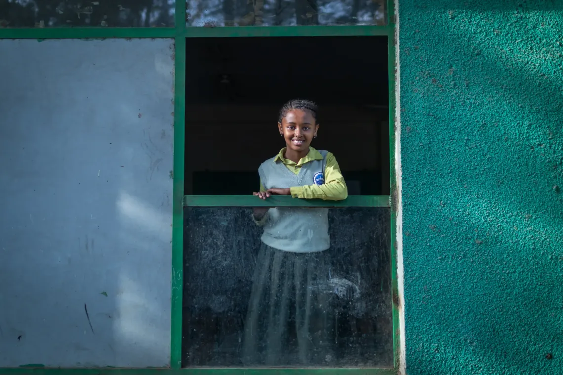 A young female student looking out the window of her classroom