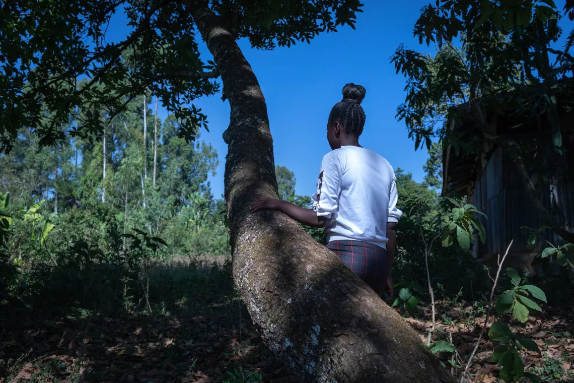 FGM survivor standing against a tree and showing her back