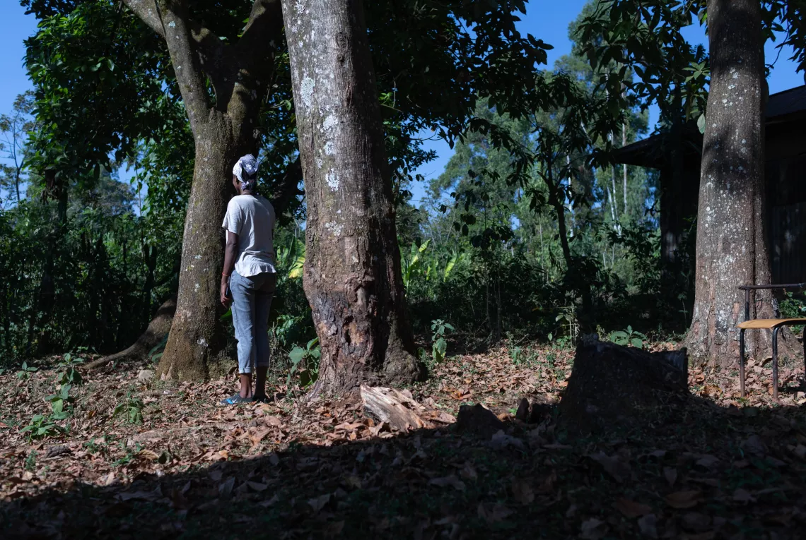 FGM survivor standing next to a tree and showing her back