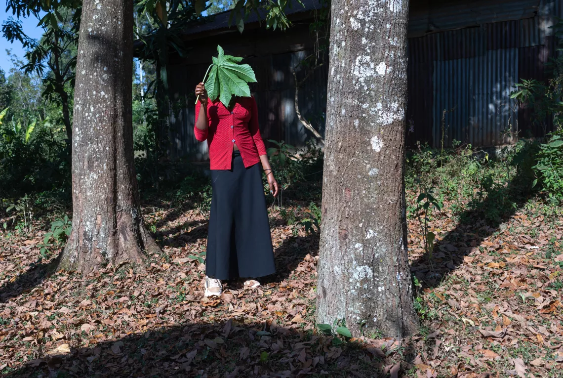 FGM survivor standing in between two trees and showing her back