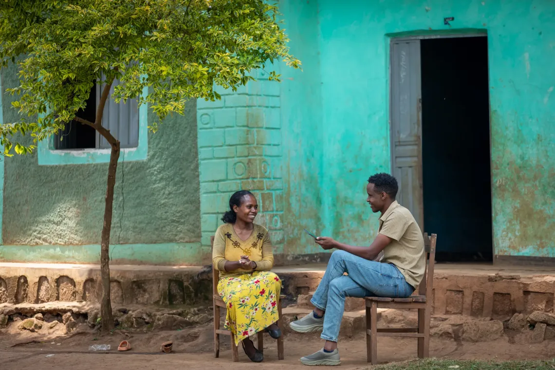 A man and a woman talking sitting on a chair and facing each other. 