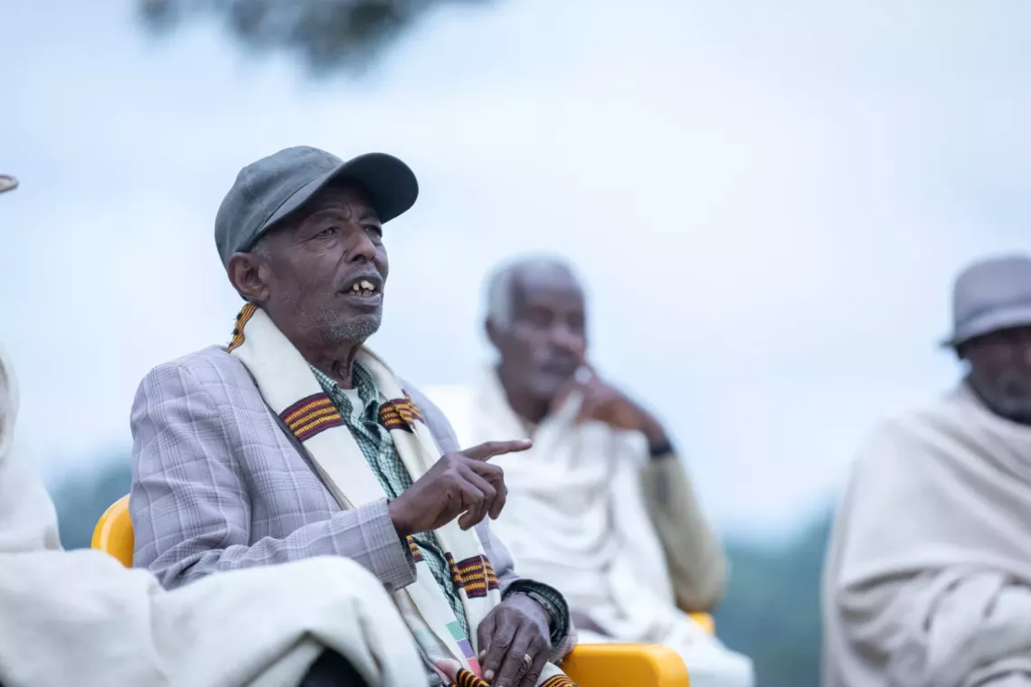 Community leader sitting and speaking among other leaders 