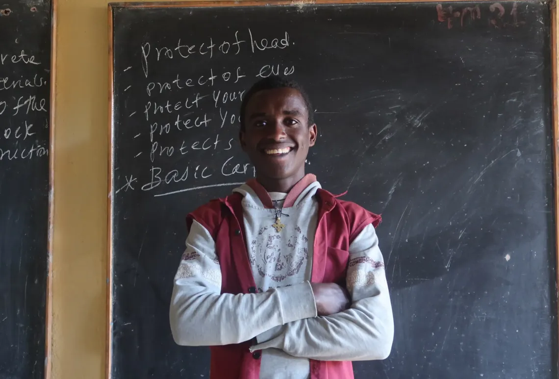Mebratu standing infront of his classroom's blackboard.