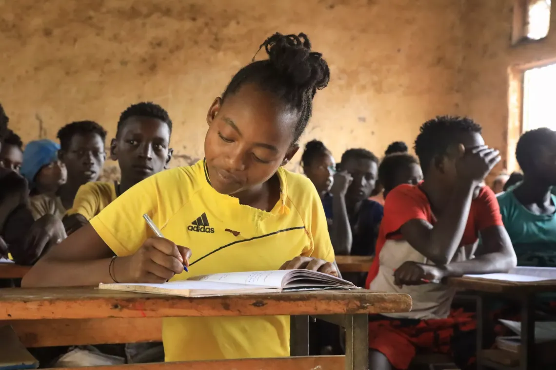 A young girl sitting at her desk and writing on her notebook