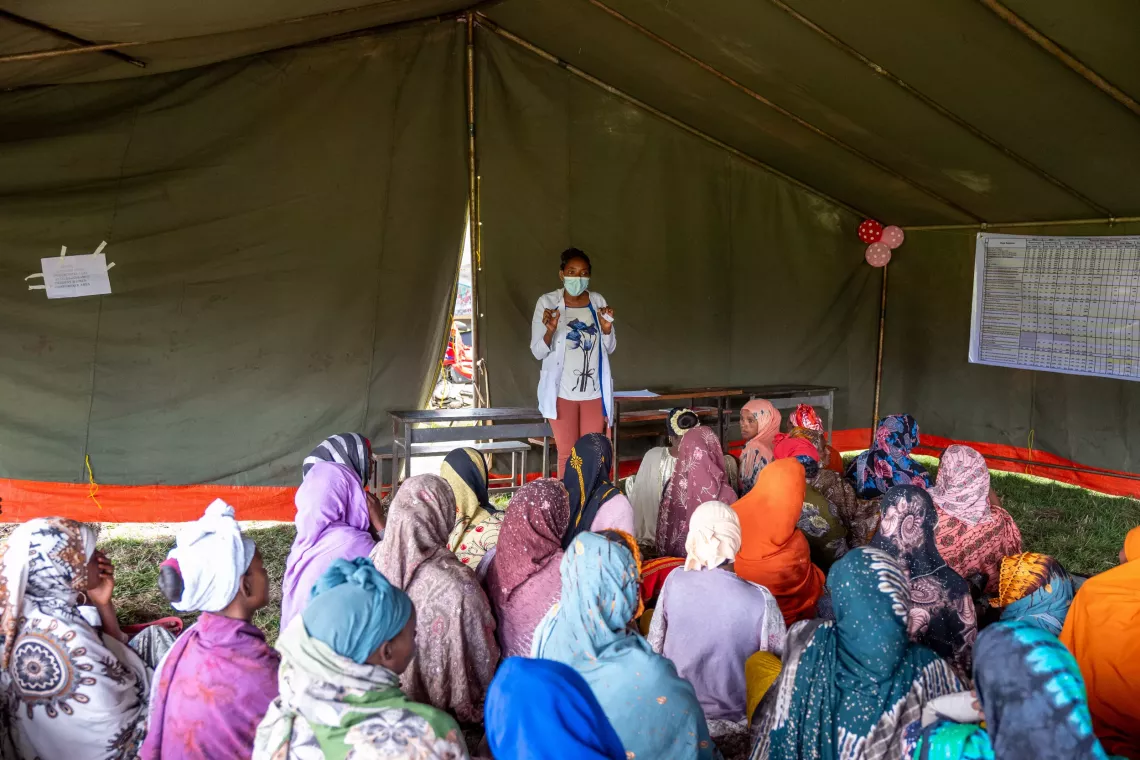 Pregnant mothers sitting together and listening to a health worker give counseling about maternal health. 