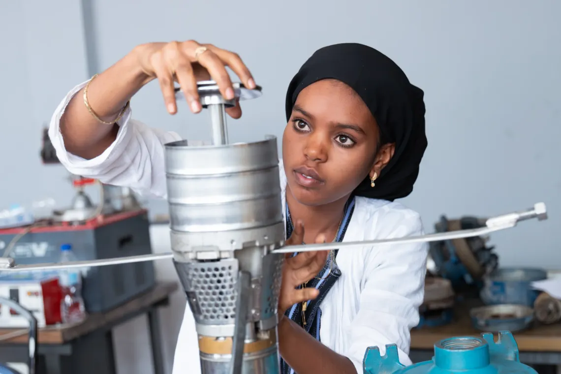 A young women carefully assemble a water pump.