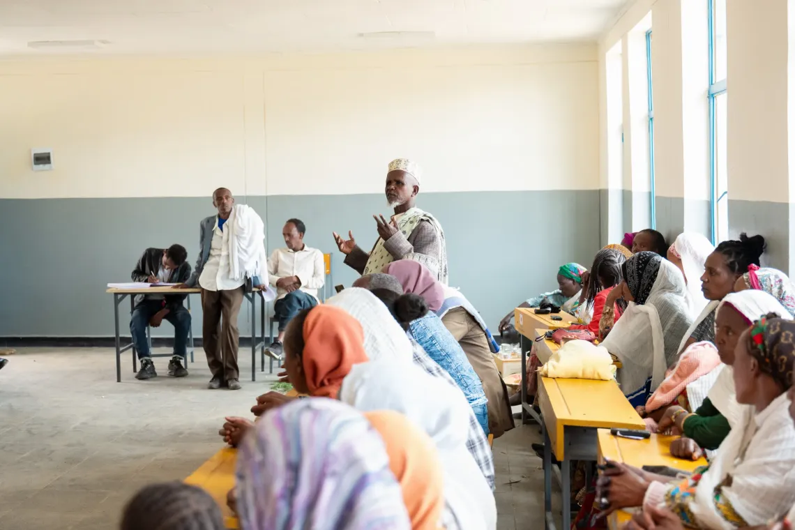 A community meeting session and a relligeuos leader talking 