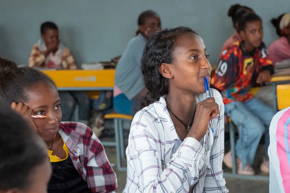 A young girl attentively listen to her teacher in class