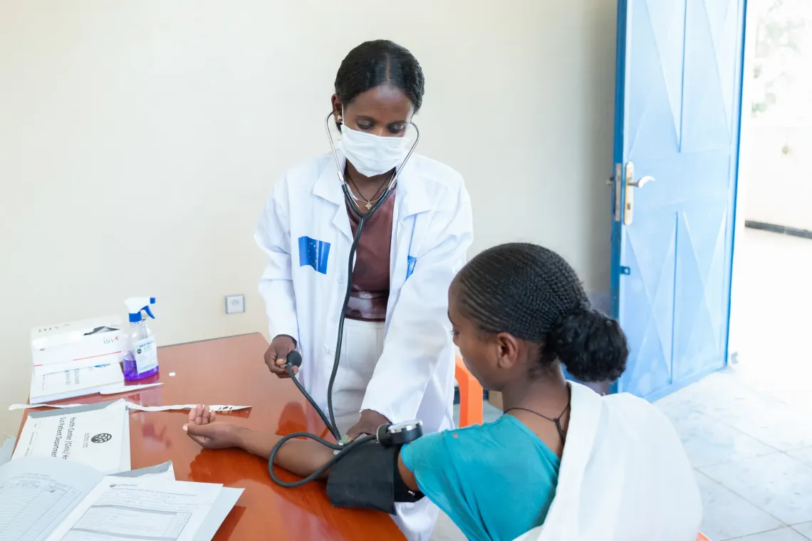 A health worker measuring a blood pressure of a young woman. 