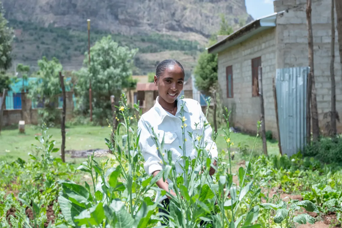 A young woman stands inside a vegetable farm 