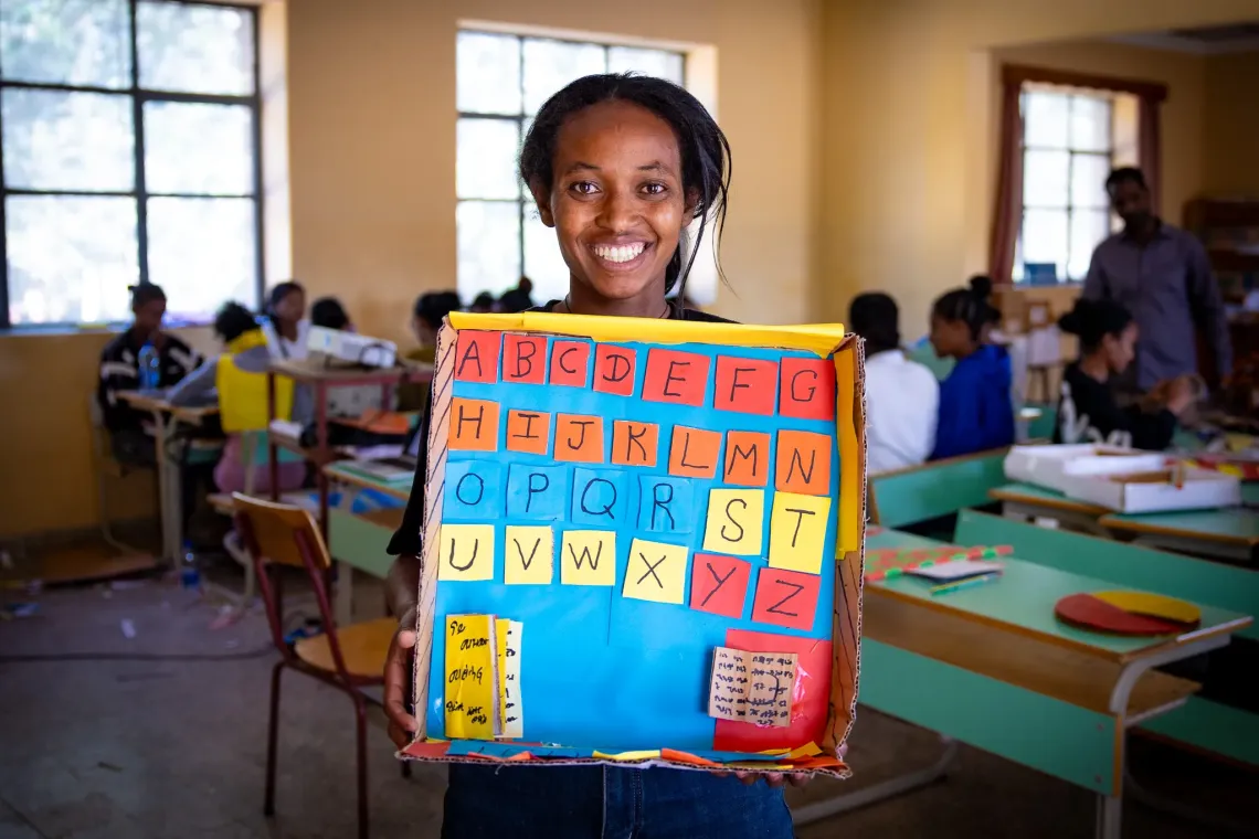 Tirhas, 27, holding up an alphabet board for early childhood education that she made in the Biqu Wetat training center.