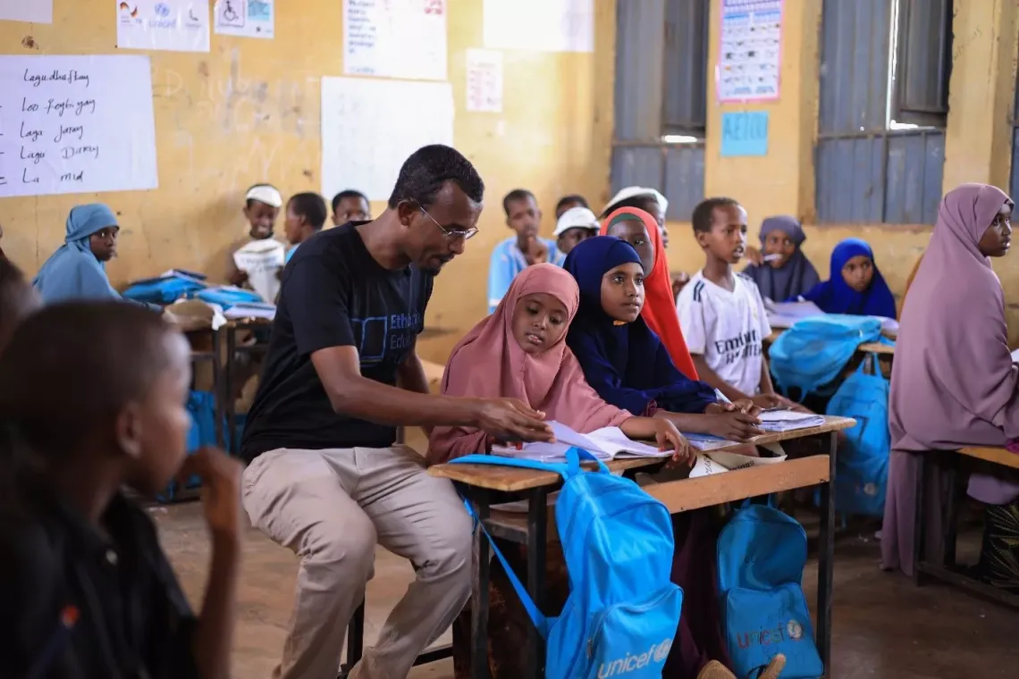 UNICEF education specialist helping students with their classwork in a SPEED school clasroom