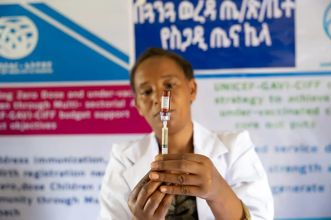 A health worker prepares a vaccine holding the vial up.