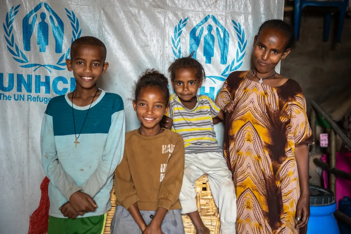 Adiam (second from the left) posing in front of her makeshift shelter with her mother and her two siblings.  