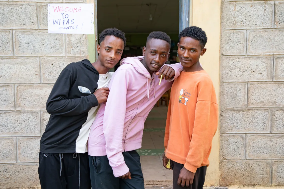 Sekuaru, Mesay, and Temesgen standing in front of a school block