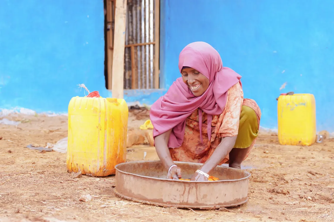 A women sitting on the ground and washing her cloth