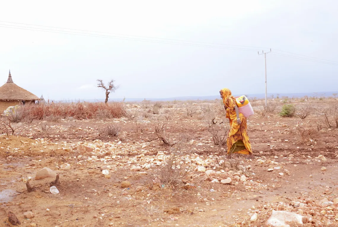 A women walking while carrying a jerrycan