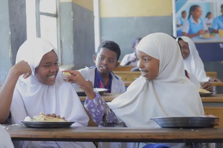 Two young female students enjoying their school mean that incudes egg