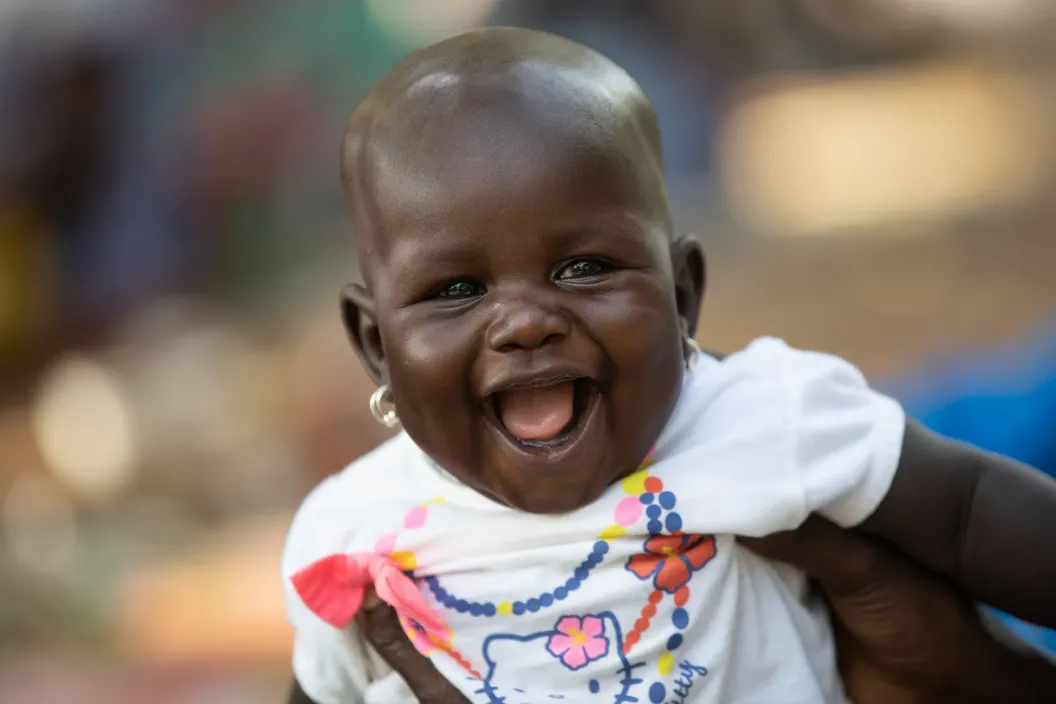 A close up of little baby smiling while her mother holding her