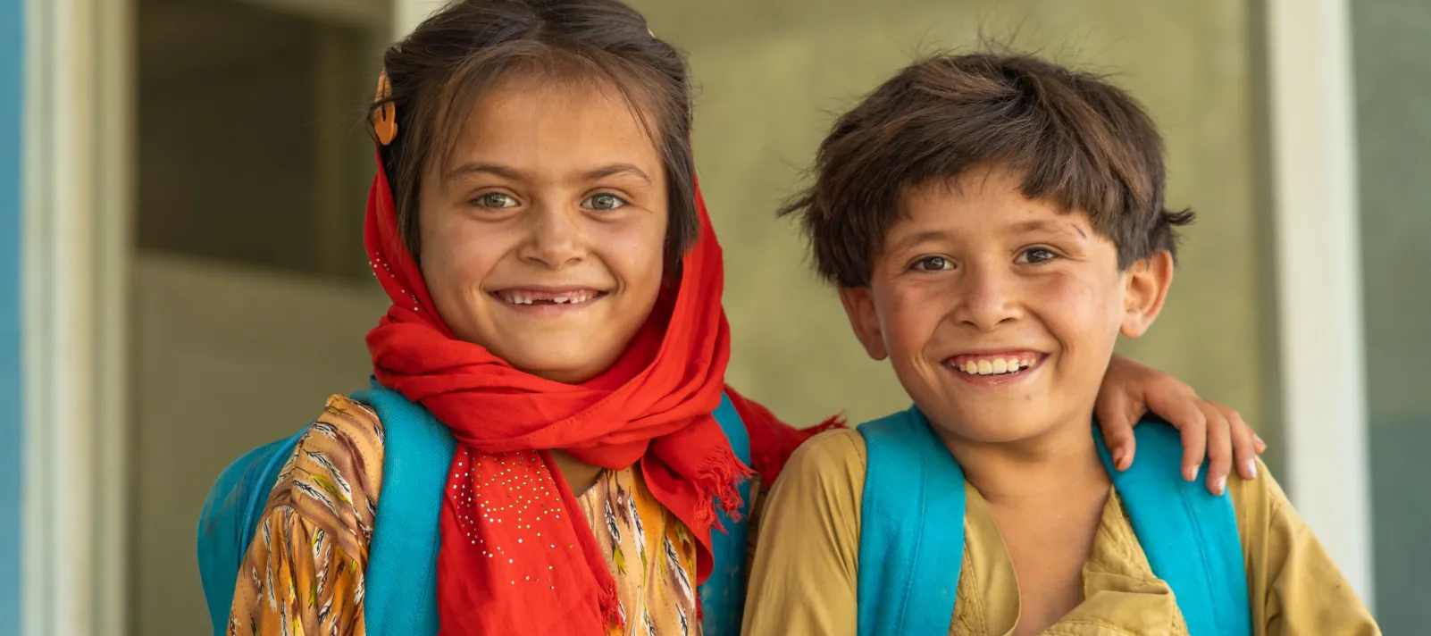 Smiling sister and brother outside clssroom.