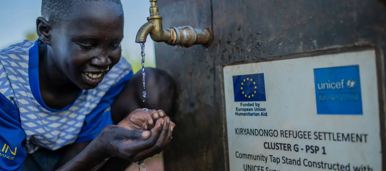 Boy drinking at water facility installed by UNICEF