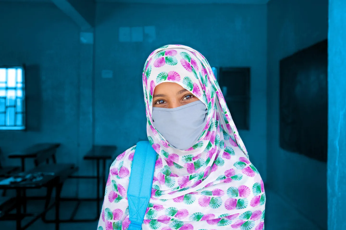 The young Fatimetou poses with her cloth mask in front of her classroom, Mauritania.
