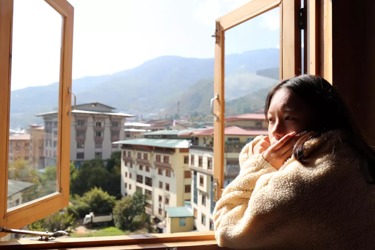 Tenzin Yangtso, 17, rests by an open window at her house.