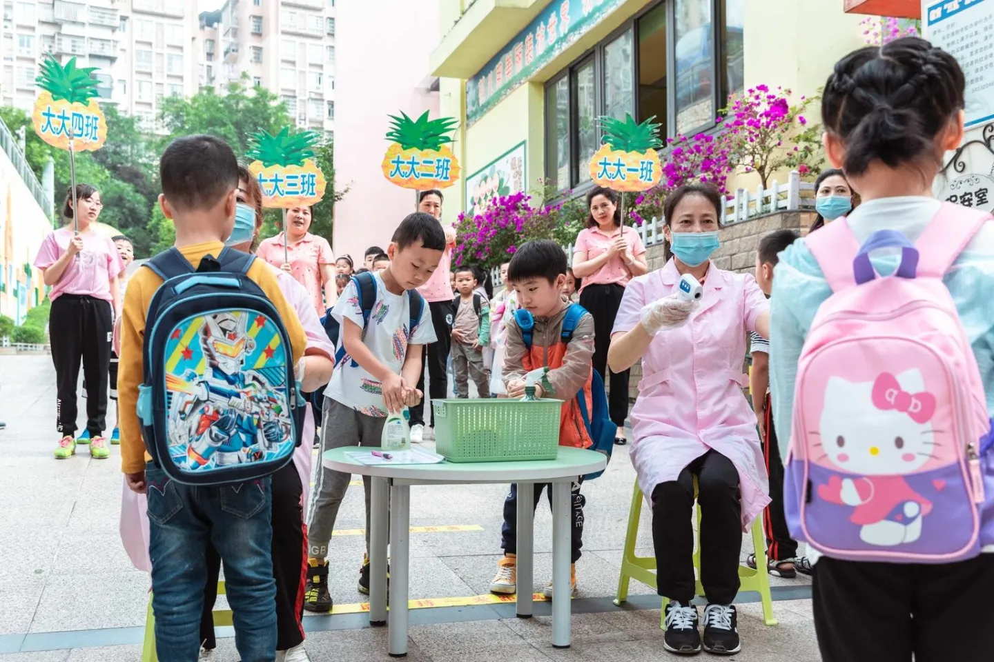 Children have their body temperature checked and use hand sanitizer before entering Zhongzhou Kindergarten, China