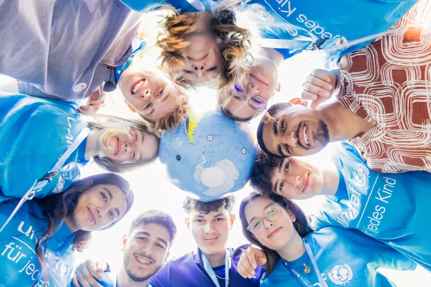 Participants and globe in a team circle at the 2024 YouthFestival.
