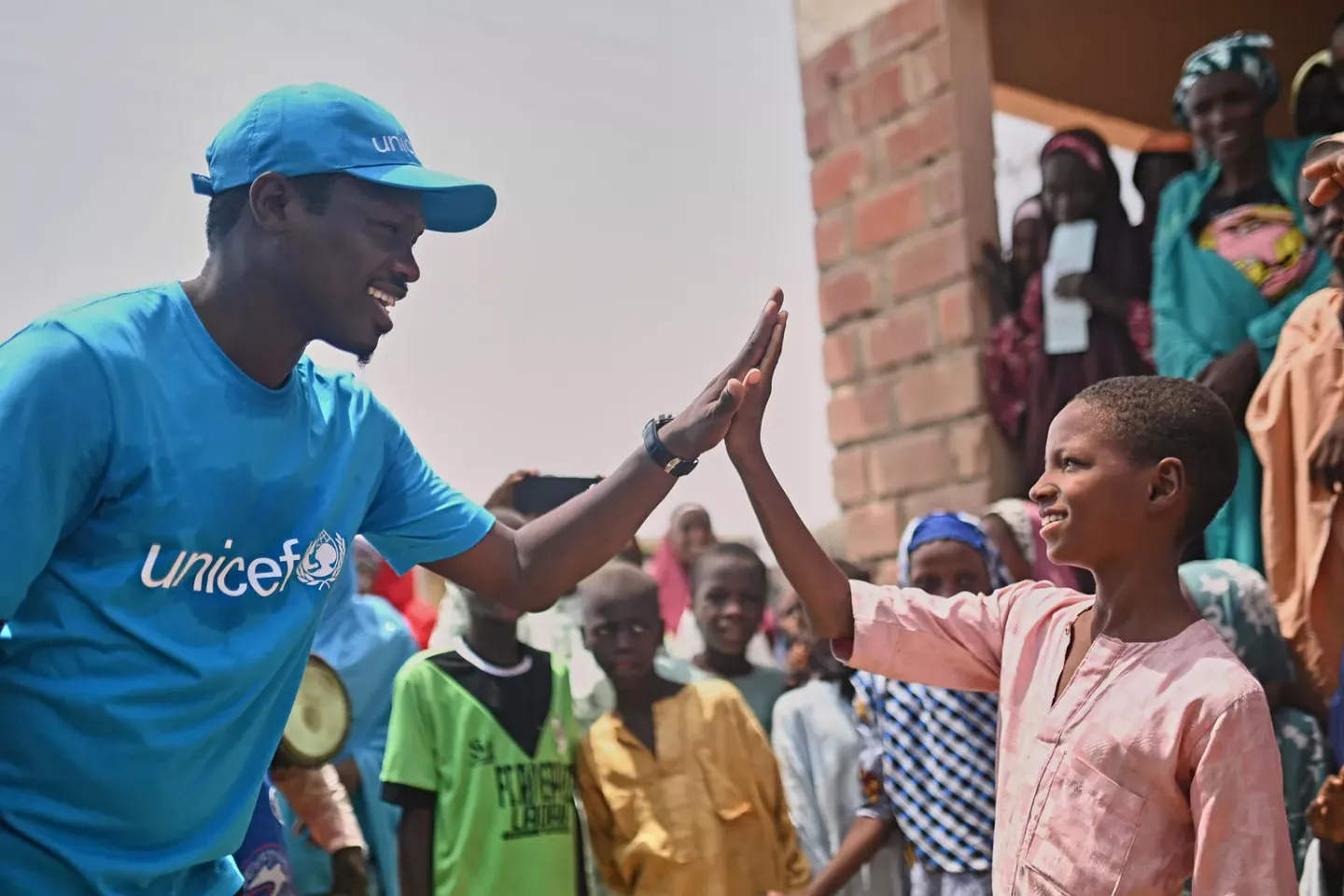 Ali Nuhu, A Nigerian Actor and Unicef Champion gives a high five to a boy during a visit to Tsamiyya Babban PHC, Kano State.