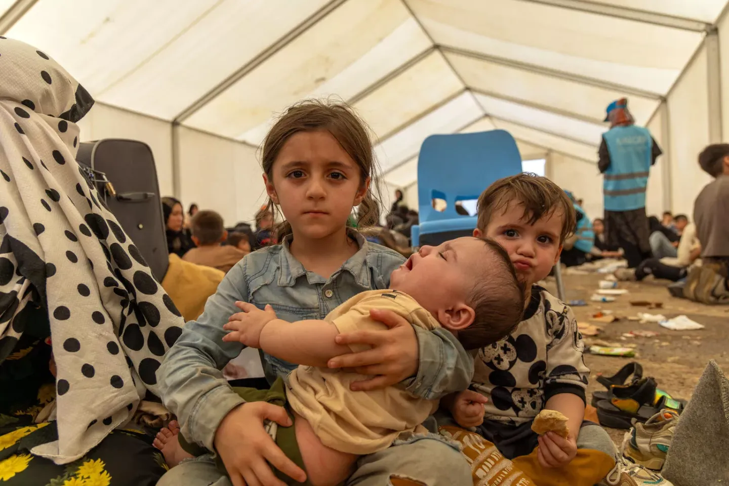 On 2 July, 5-year-old Khozaima, sits with her siblings and mother inside a large tent set up in the reception area at the Islam-Qala border point. Originally from the northern Afghan province of Badakhshan, she and her family of eight returned to Afghanistan after having left to Iran escaping economic hardship in Afghanistan. They had lived as undocumented migrants in Iran for several years. 