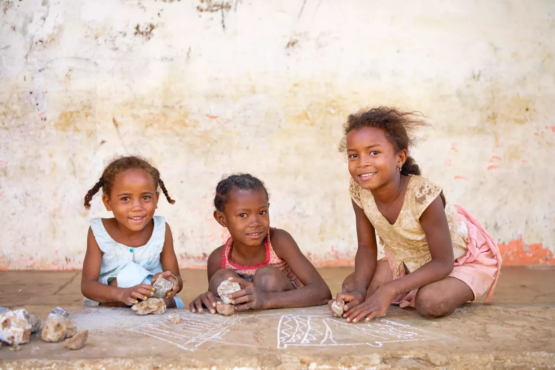 Smiling young girls playing under the playground of a classroom - WASH intervention