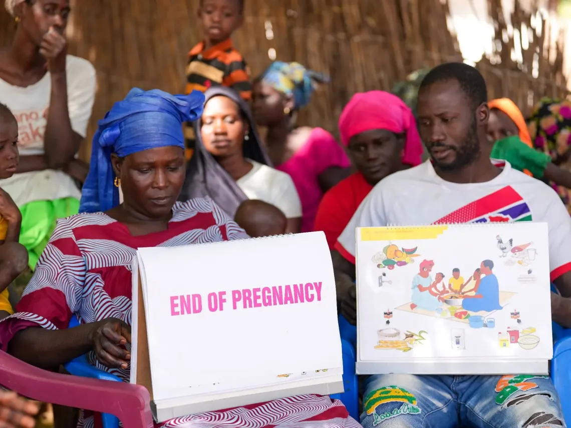 Halima Mbye leads a community session in Cheken, North Bank Region, using a counselling flipchart that follows a mother from pregnancy through to her baby's first feed.