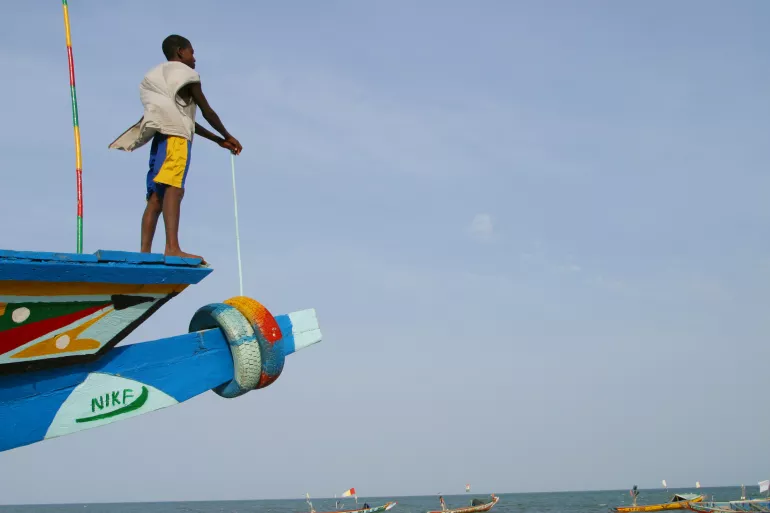 A boy stares at the sea as he stands on the end of a boat