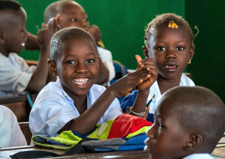 Children smile at the camera in class